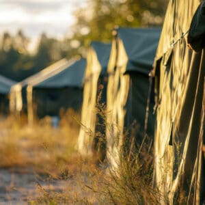 Campement militaire avec plusieurs tentes tactiques installées en pleine nature.