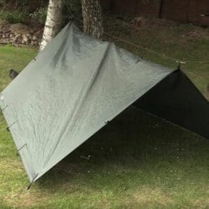 Tarp militaire monté en abri de survie, idéal pour le bushcraft et les activités en plein air.